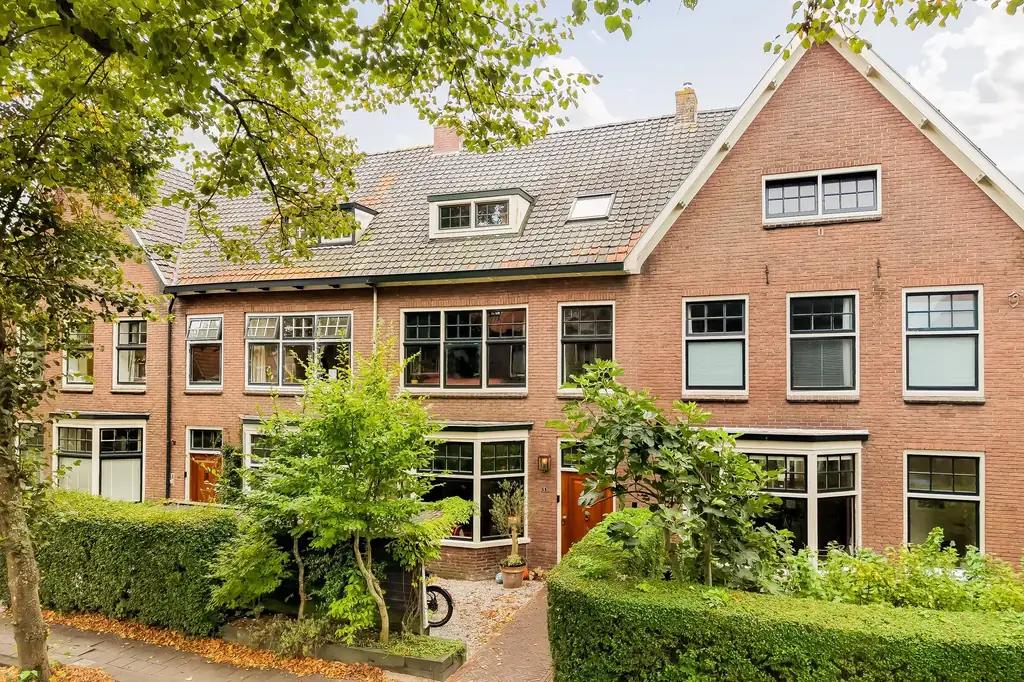 Rij vooroorlogse bakstenen woningen in een groene straat